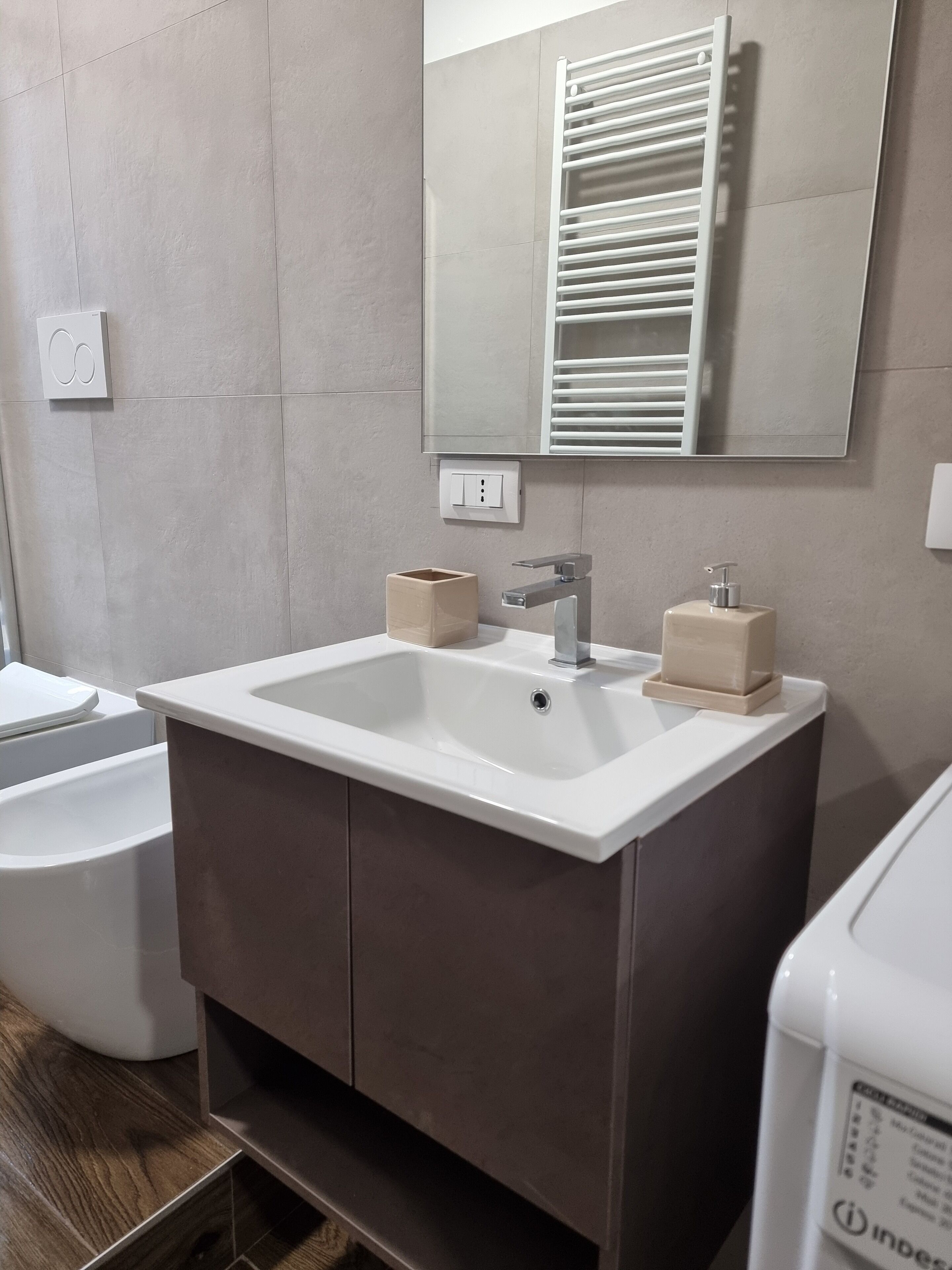 Un baño con un lavamanos blanco, un espejo encima y un perchero para toallas.