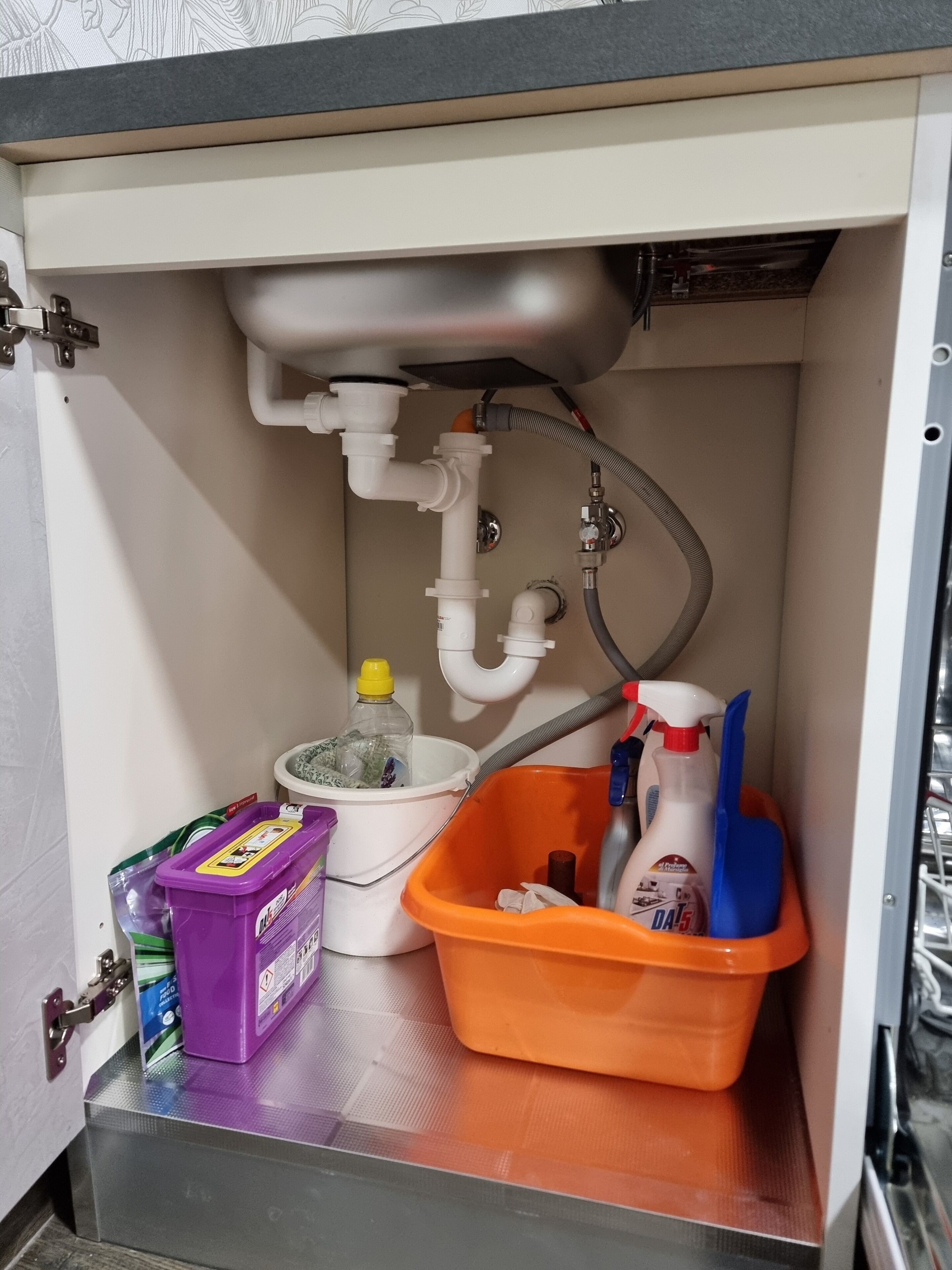 Casa de banho com sanita, lavatório e espaço para guardar produtos de limpeza.