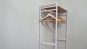 A white metal wardrobe with multiple shelves and wooden hangers. - TWO-ROOM APARTMENT with kitchen-PAVIA-near the center (Pavia)
