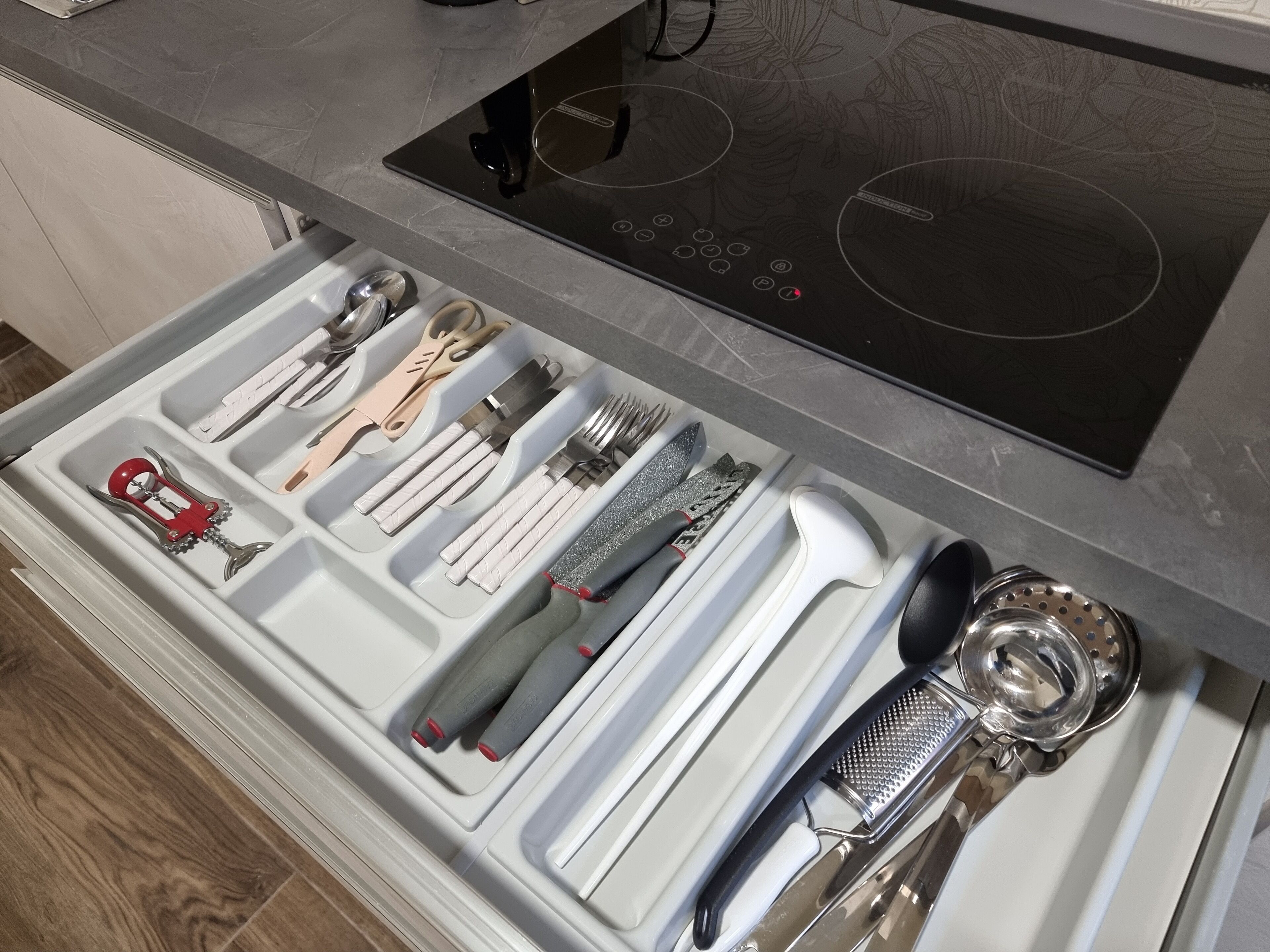 A kitchen drawer with utensils and a built-in induction cooktop.
