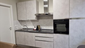 A modern kitchen with grey cabinets, a stainless steel range hood, and a built-in oven. - TWO-ROOM APARTMENT with kitchen-PAVIA-near the center (Pavia)