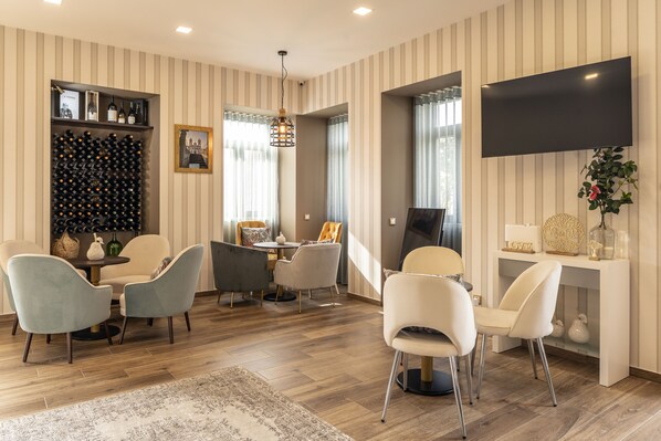 Un salon moderne doté d’un meuble à vin, d’un téléviseur à écran plat et d’un coin repas avec des chaises et une table.