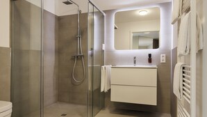 A modern bathroom with a glass-enclosed shower, a white vanity with a mirror, and a towel rack. - homie hotel zur stadt mainz (Würzburg)