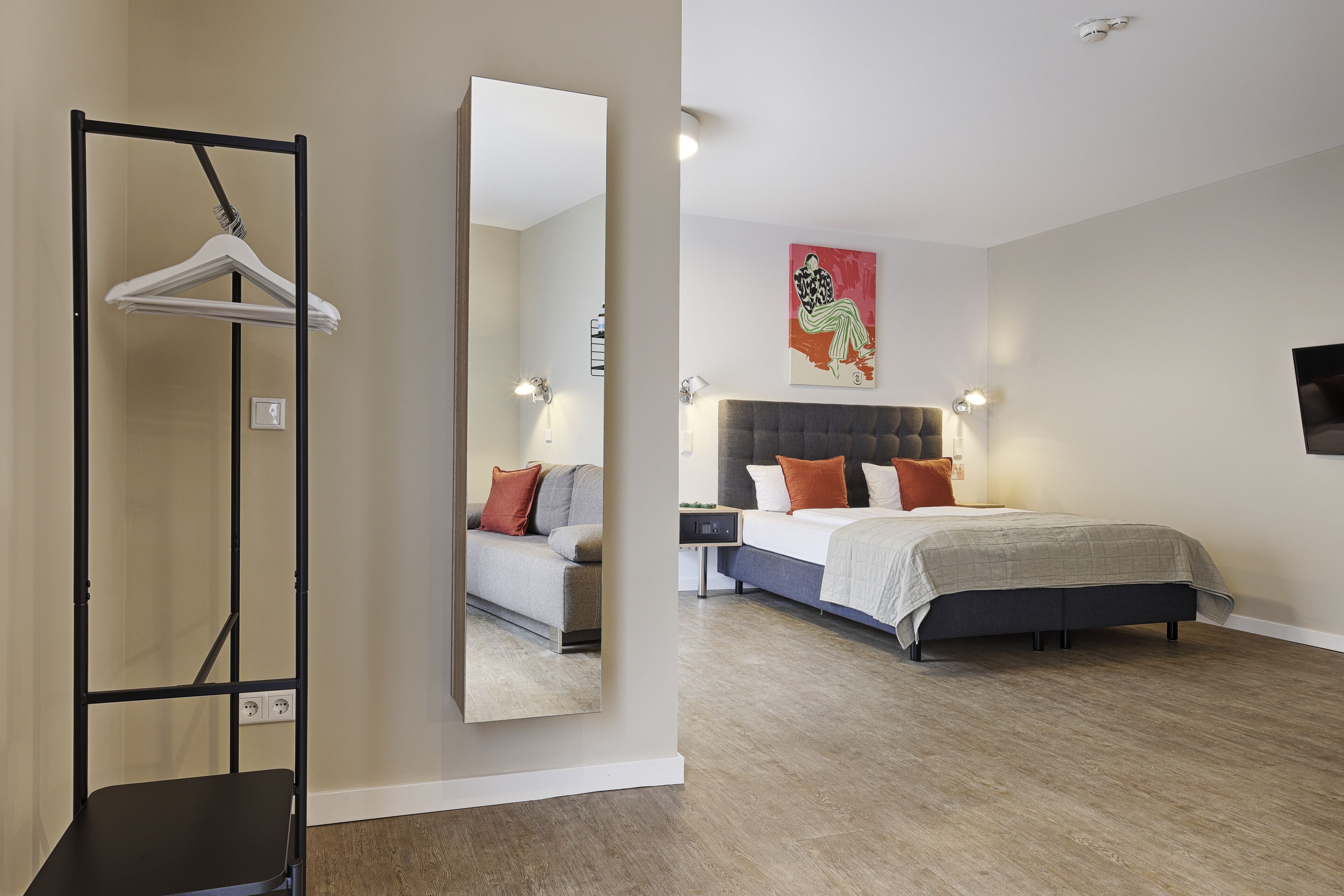 Un dormitorio moderno con una cama grande, una mesita de noche y un perchero.