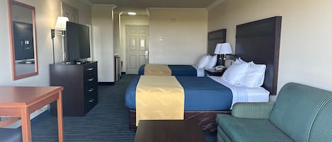 Una camera d'albergo con un letto, una scrivania, un televisore, una lampada e un divano.