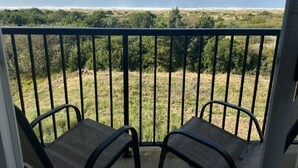 A balcony with two chairs and a view of a grassy landscape with trees and a distant horizon.