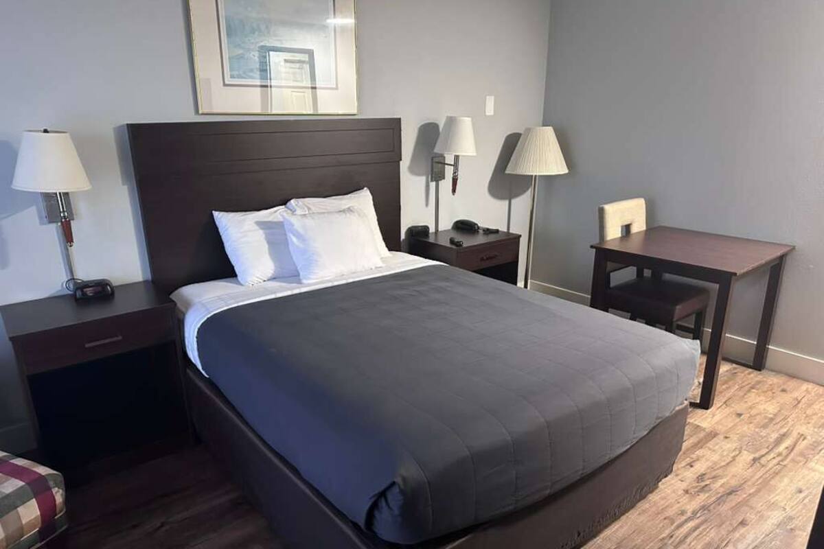 Une chambre d’hôtel avec un grand lit, des tables de chevet, un bureau et des lampes.