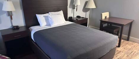 Una habitación de hotel con una cama grande, mesitas de noche, un escritorio y lámparas.