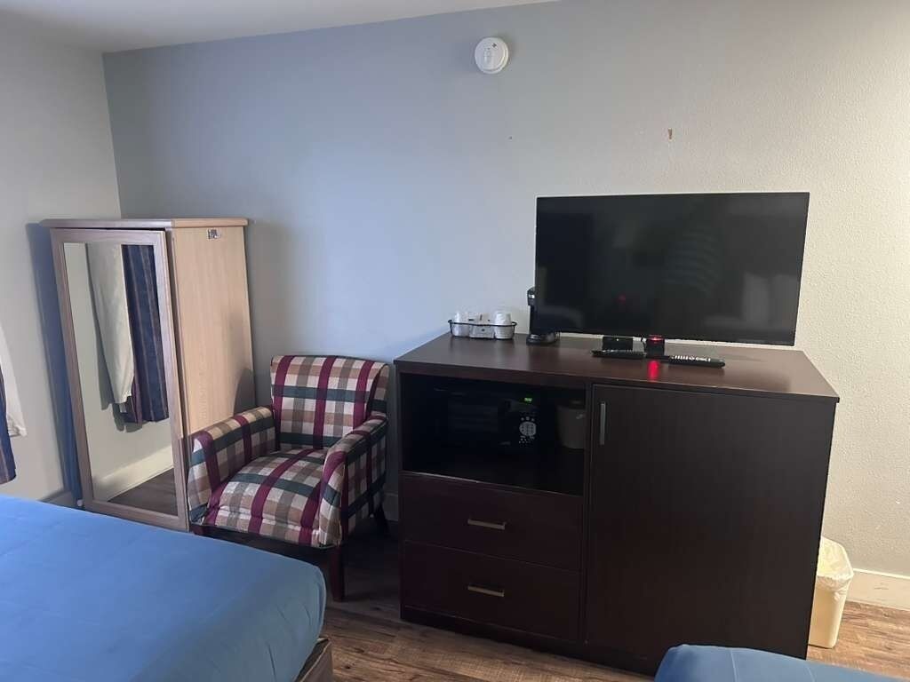 Habitació d'hotel petita amb llit, escriptori amb televisió, cadira i armari.