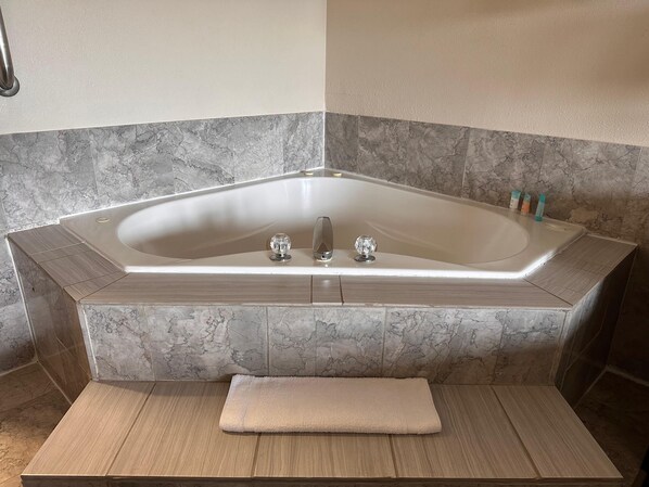 A modern bathroom with a freestanding bathtub, marble tiles, and a wooden bench.