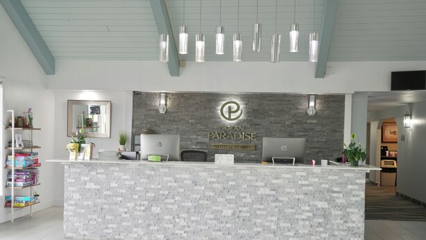 A reception desk with a grey and white patterned wall, a logo, and a sign that reads "Ocean Paradise Hotel & Resort."