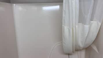 A standard bathtub with a faucet and a shower curtain rod.