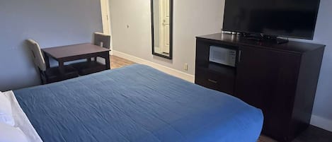 Een hotelkamer met een groot bed, een bureau, een stoel, een televisie en een spiegel.