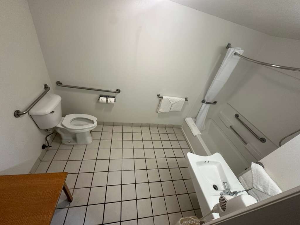 A small, clean bathroom with a toilet, bidet, sink, and grab bars.