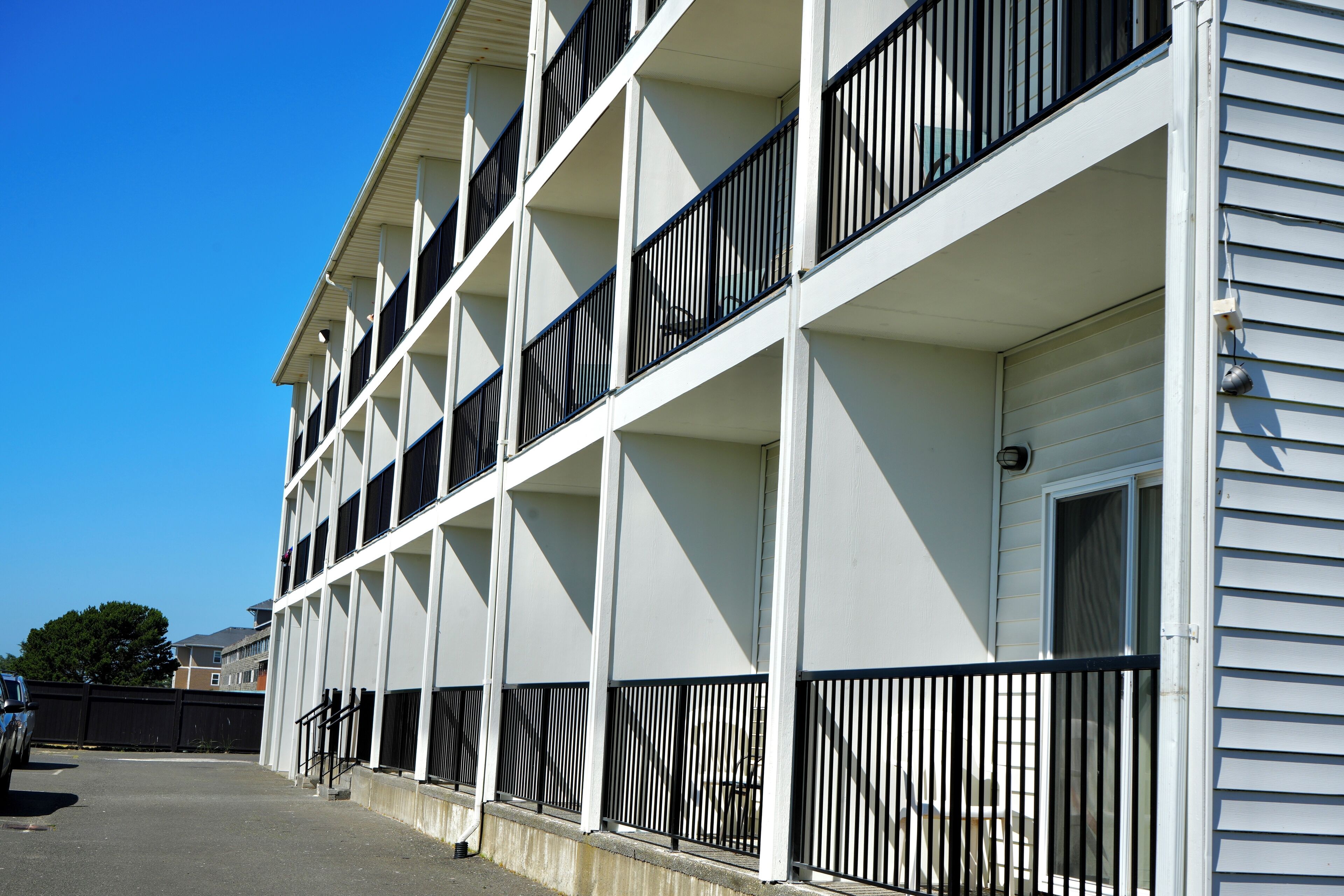 Un edificio de varios pisos con balcones, una puerta de garaje y cielo despejado.