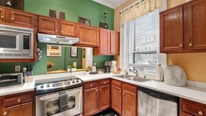 A kitchen with wooden cabinets, a stainless steel stove, a microwave, and a dishwasher. - The Louisville Cottage | Prime Location | Near DT! (Louisville)