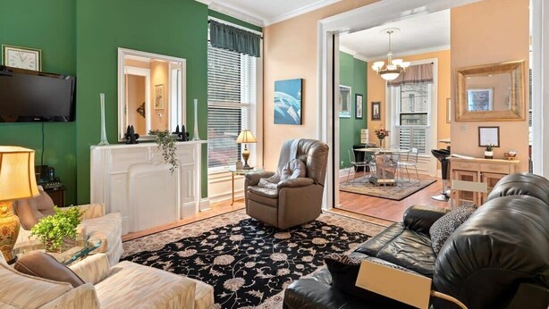 A living room with a fireplace, a sofa, a chair, and a television. - The Louisville Cottage | Prime Location | Near DT! (Louisville)