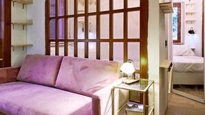 A room with a pink sofa, a bedside table with a lamp, and a bed with a white comforter. - CloClo House: Design & Vintage above Metro: Nolo Area (Milano)