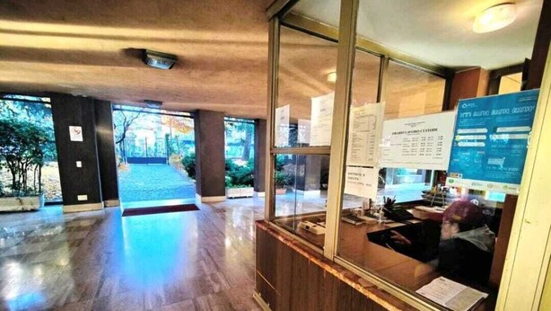 A reception area with a wooden reception desk, glass windows, and a view of the outdoors. - CloClo House: Design & Vintage above Metro: Nolo Area (Milano)