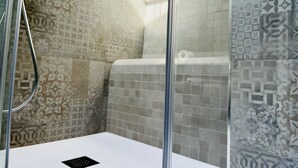 A bathroom with patterned tiles, a shower area, and a toilet. - Eufonia del Mare (Finale Ligure)