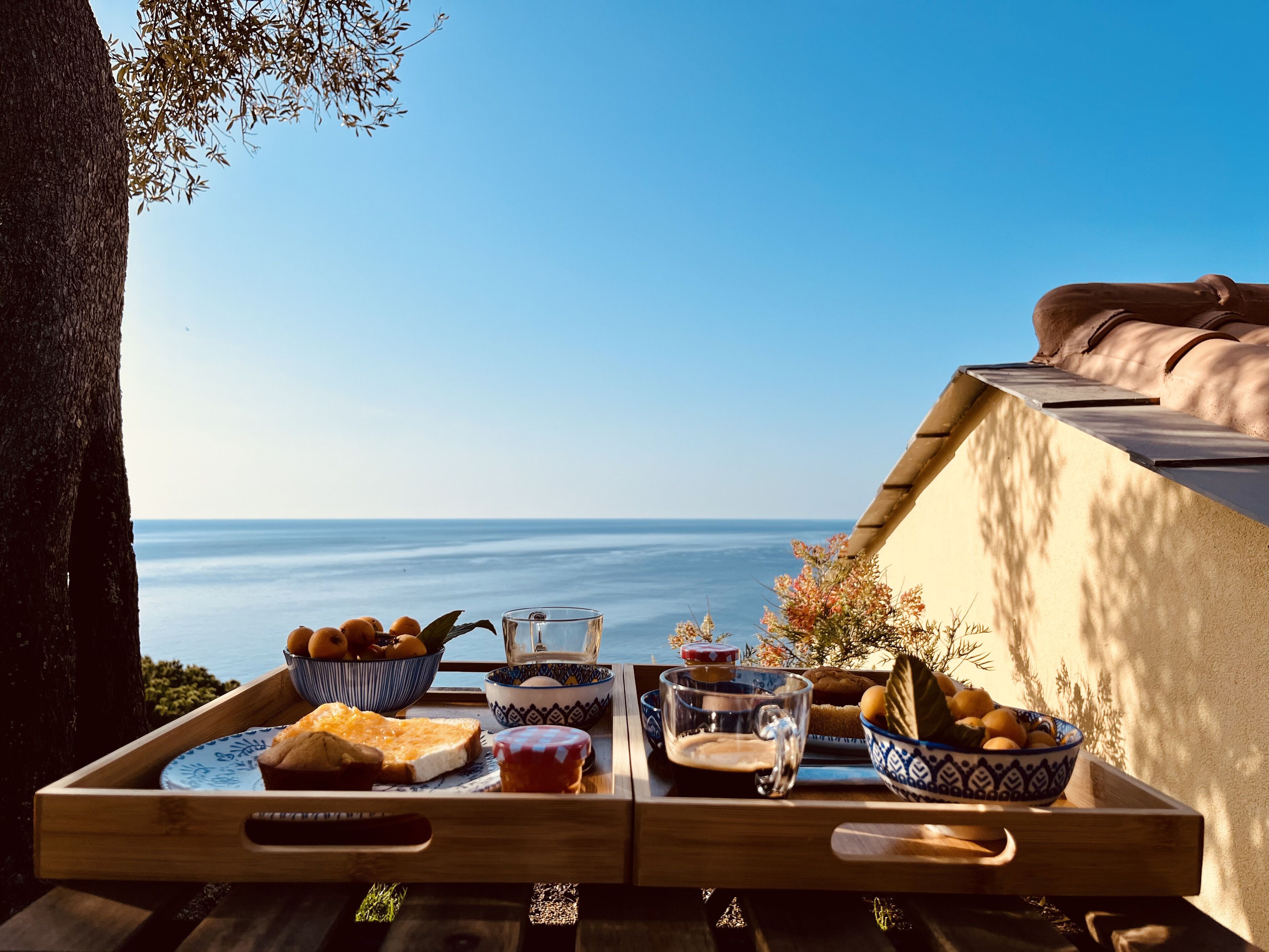 A wooden tray with food and drinks, overlooking a coastal view.