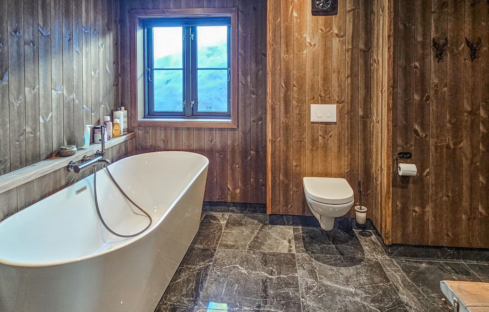 Un bagno con una vasca freestanding, un water e una finestra.