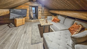 A cozy attic room with a large TV, wooden furniture, and a comfortable sofa. - Gorgeous home in Passebekk with kitchen (Passebekk)