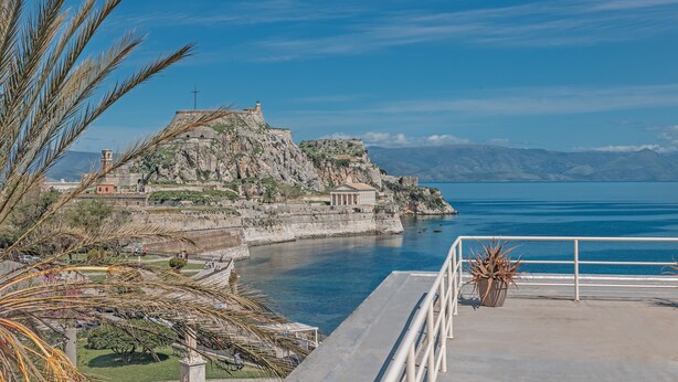 Une vue sur la côte, avec un fort historique, un ciel bleu dégagé et une mer calme.