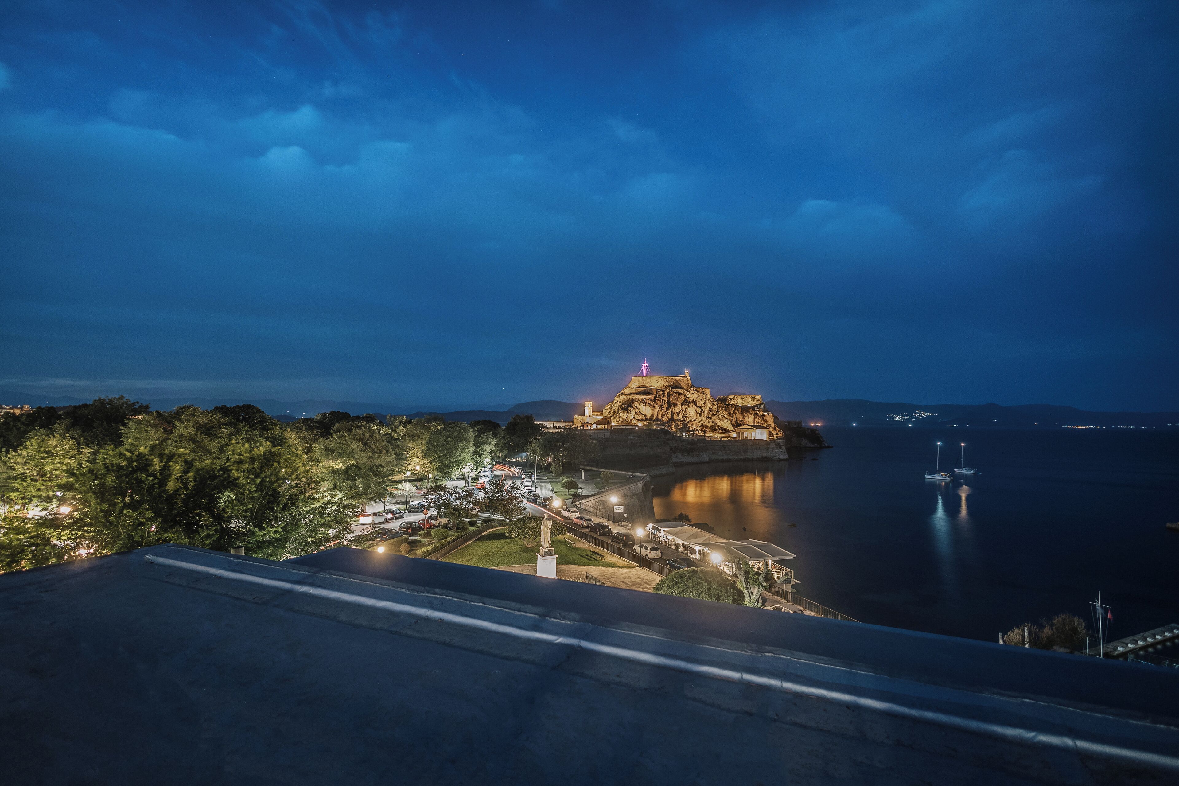 Vista sulla costa con un forte storico, un porto turistico e uno skyline al crepuscolo.