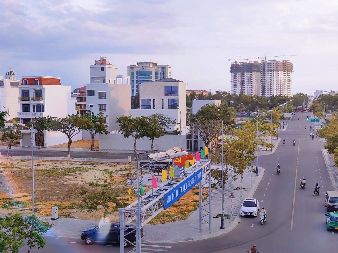 A city street with modern buildings, a construction site, and a pedestrian crossing.