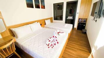 A hotel room with two beds, a wooden floor, a TV, and a shower area.