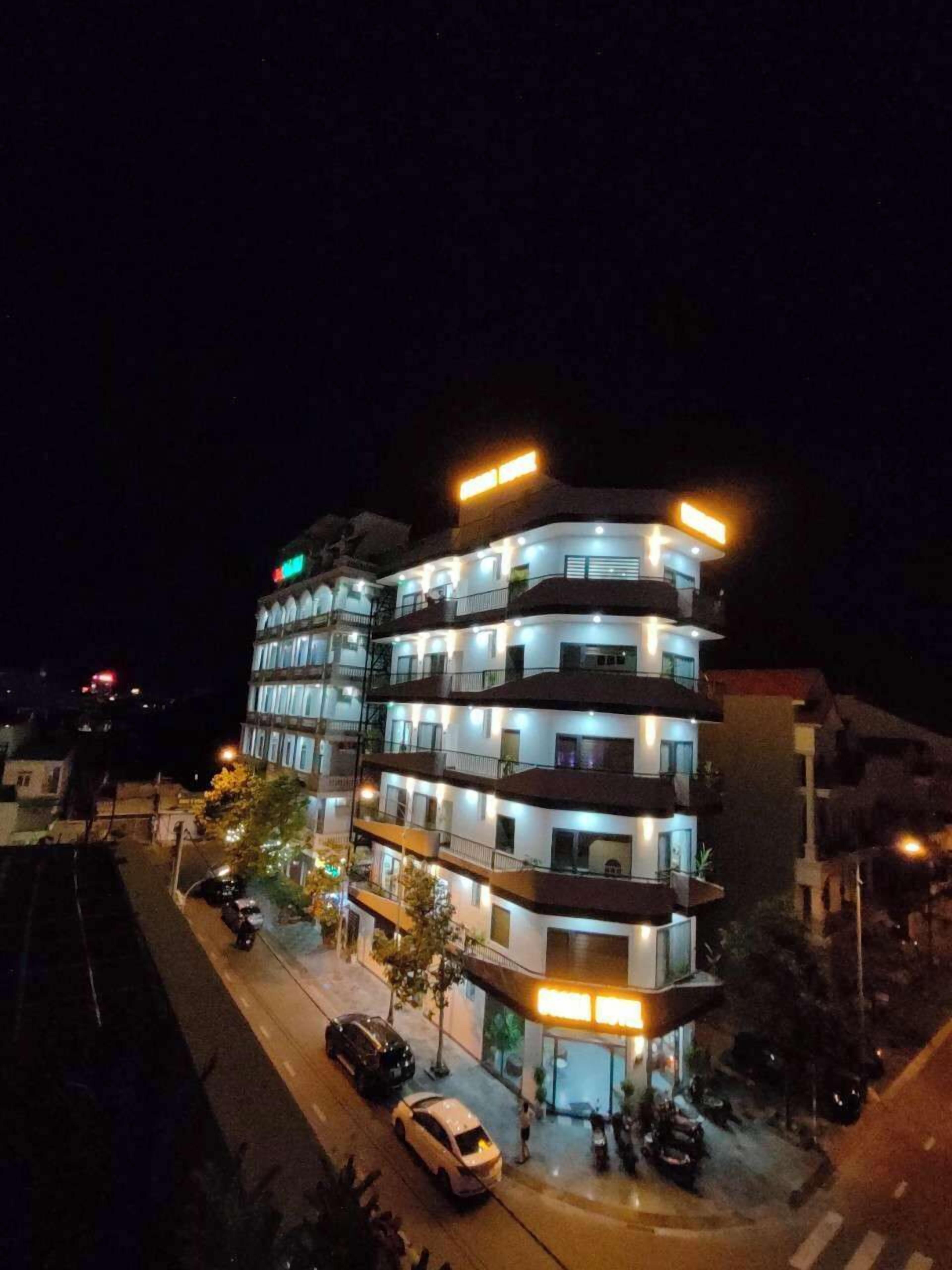 A multi-story hotel with illuminated balconies and a ground-level entrance.