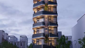 A modern multi-story building with balconies, large windows, and a ground-level entrance.