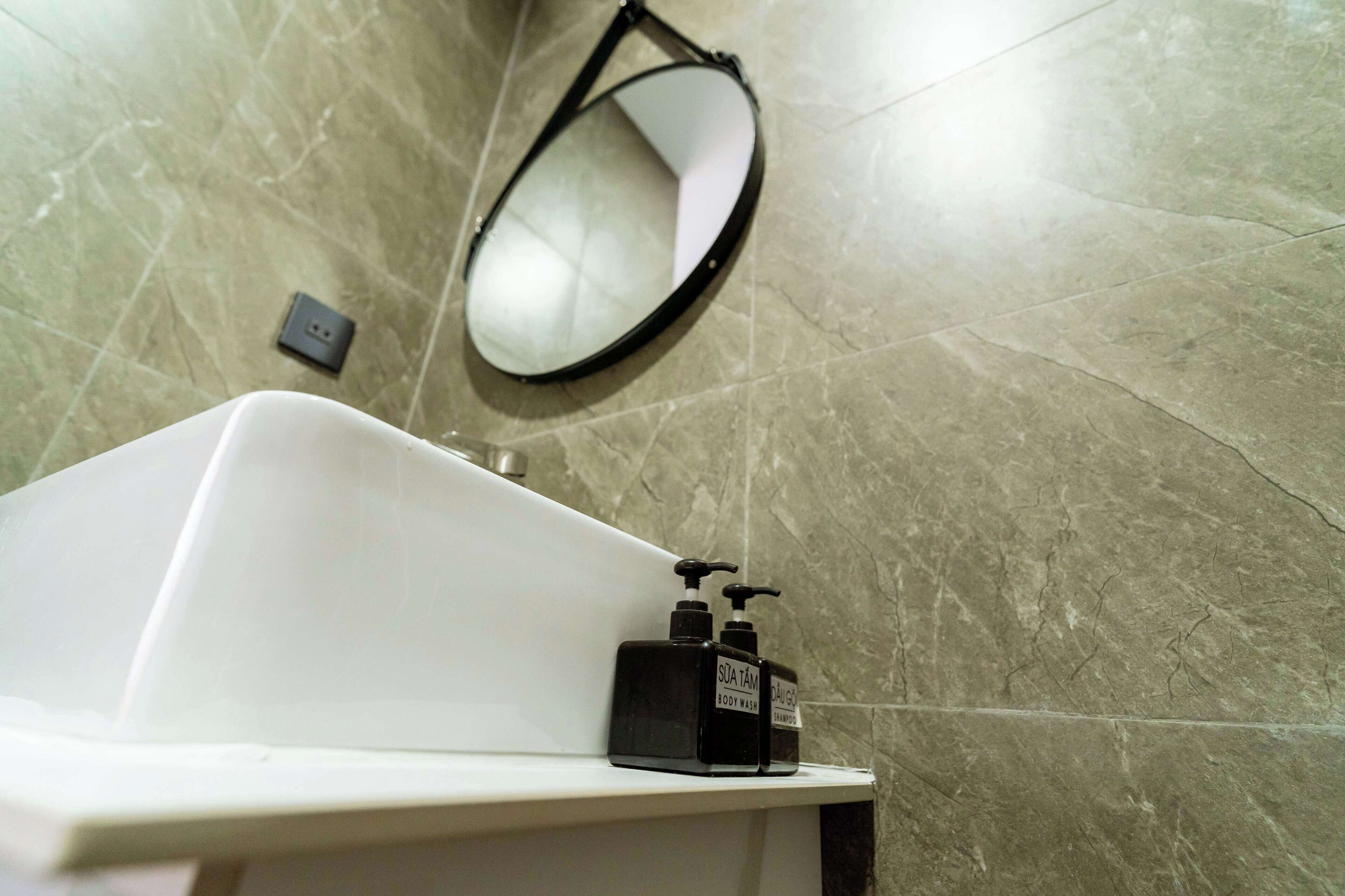 Un baño con una bañera blanca, un dispensador de jabón negro y un espejo montado en la pared.