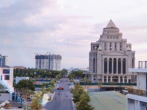 A large, historic building with classical architecture, a wide street in front, and modern buildings in the background. - Osaka Boutique Phan Thiet Hotel (Phu Thuy)