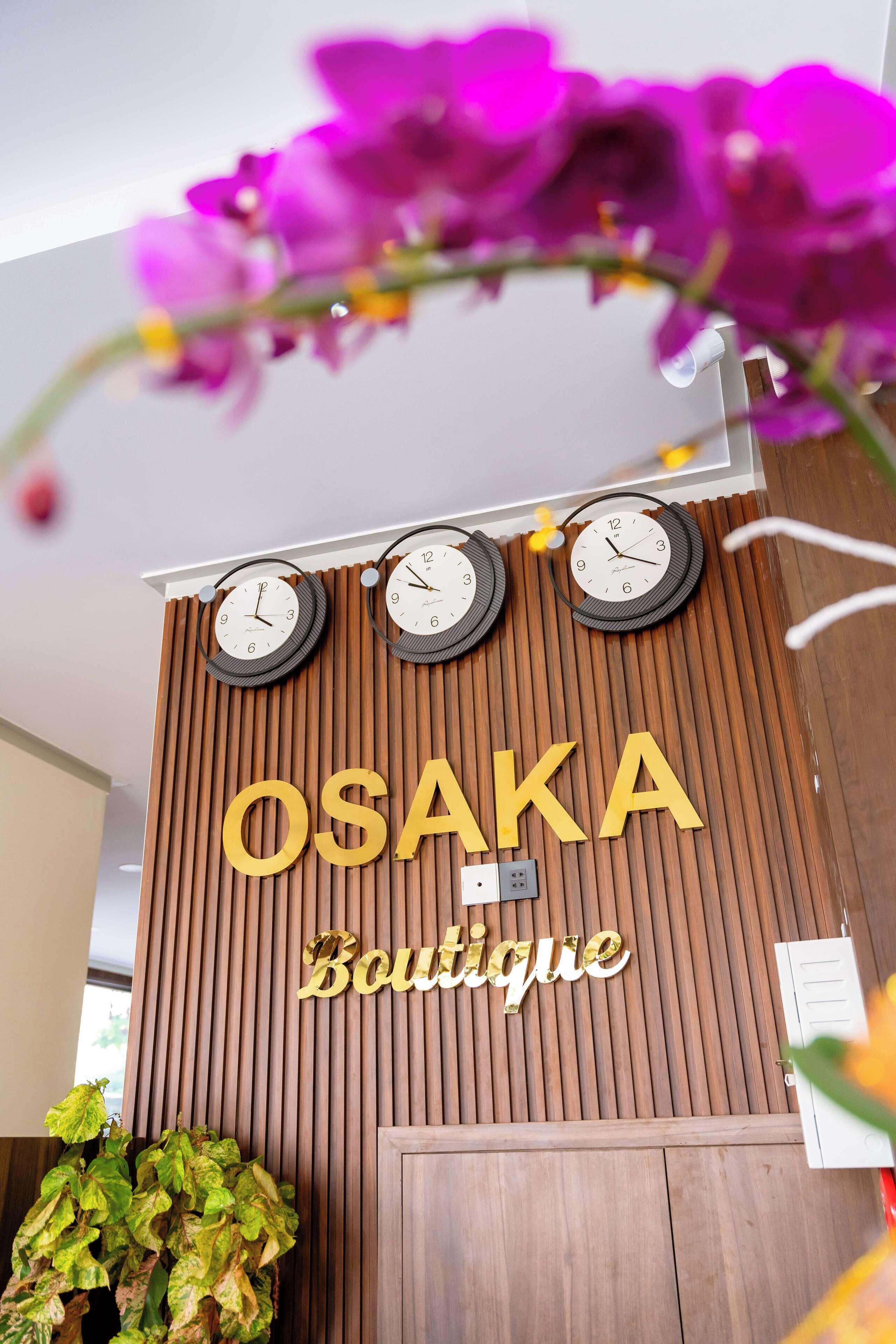A wooden wall with the name "OSAKA Boutique" and three clocks.