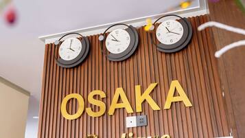 A wooden wall with the name "OSAKA Boutique" and three clocks.
