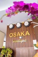 Pared de madera con el nombre "OSAKA Boutique" y tres relojes.