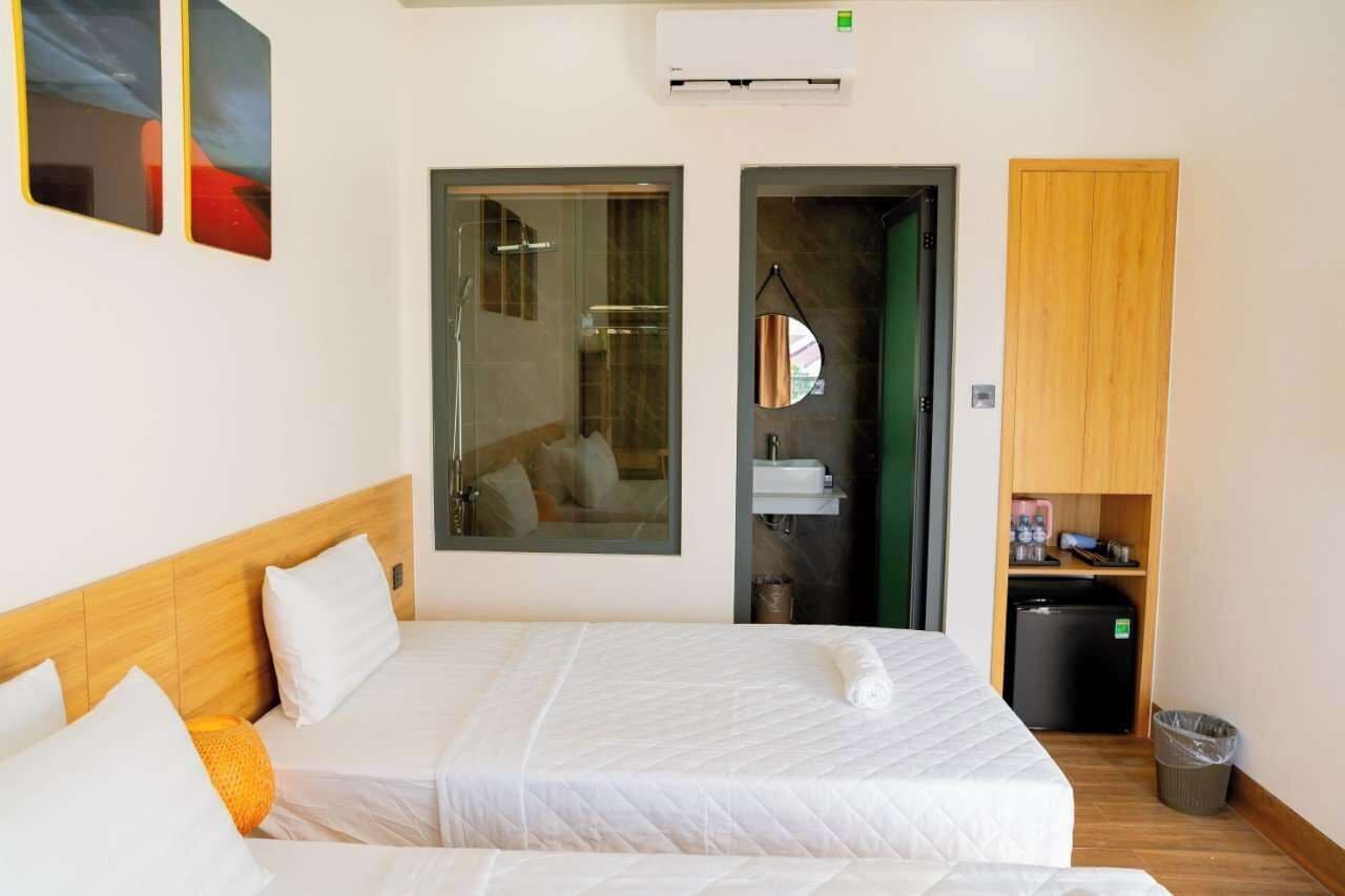 A hotel room with a large bed, a small bathroom, and a compact kitchenette.