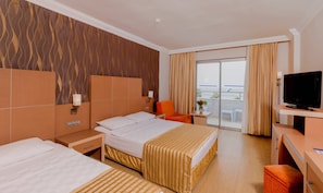 A hotel room with a large bed, a smaller bed, a desk with a television, and a balcony with a view.