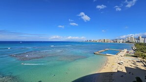 A coastal cityscape with a clear blue sky, a sandy beach, and a marina. - RELAX w/ Direct Beach Access High Flr. Sans Souci 2BD/2BA🌴Stunning Ocean Views  (Honolulu)