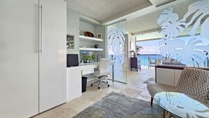 A modern home office with a desk, computer, and office chair. There is a large window with a view of the ocean. - RELAX w/ Direct Beach Access High Flr. Sans Souci 2BD/2BA🌴Stunning Ocean Views  (Honolulu)