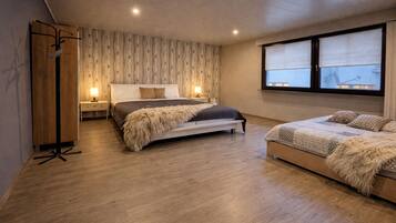 A bedroom with a large bed, a smaller bed, a wardrobe, a nightstand, and a window with blinds.
