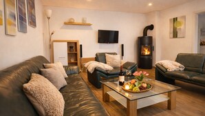 A modern living room with leather sofas, a glass coffee table, a fireplace, and a flat-screen TV. - 170 qm2 Großes, Gemütliches Haus mit Kamin und Klimaanlage. Hunde Erwünscht! (Kestert)