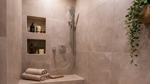 A modern bathroom with a built-in shower, a bench, and shelves with toiletries. - 170 qm2 Großes, Gemütliches Haus mit Kamin und Klimaanlage. Hunde Erwünscht! (Kestert)