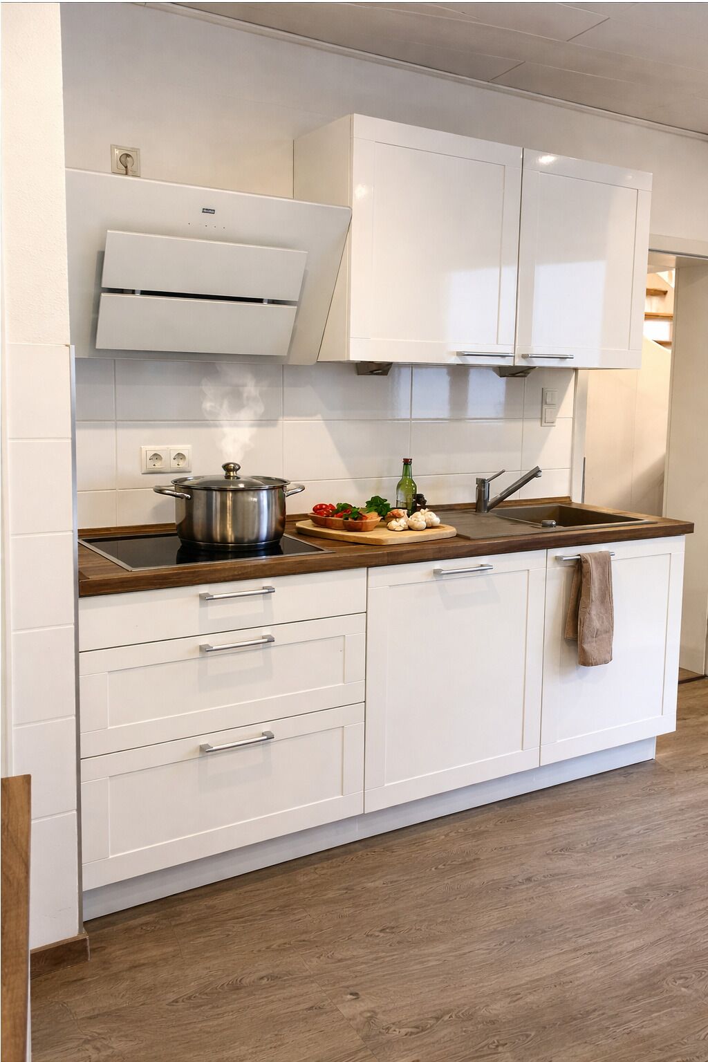 A kitchen with white cabinets, a wooden countertop, a stove, and a sink.