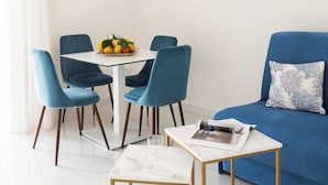 Una sala de estar moderna con un sofá azul, una mesa blanca de marco dorado y sillas azules a juego.