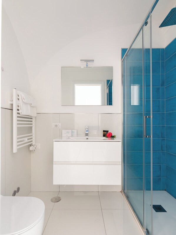 A modern bathroom with a glass shower enclosure, a white vanity, and a towel rack.