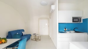 Un espacio habitable compacto con comedor, kitchenette y un sofá azul.