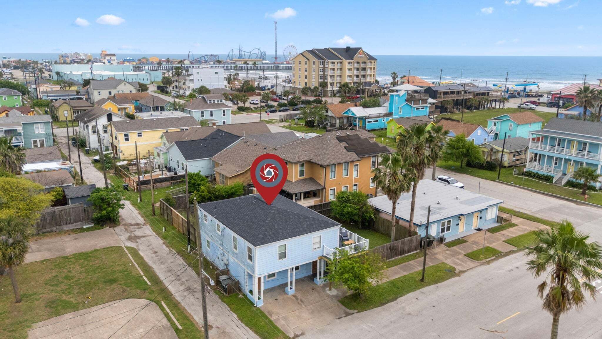 A coastal residential area with houses, a beach, and a Ferris wheel in the background.